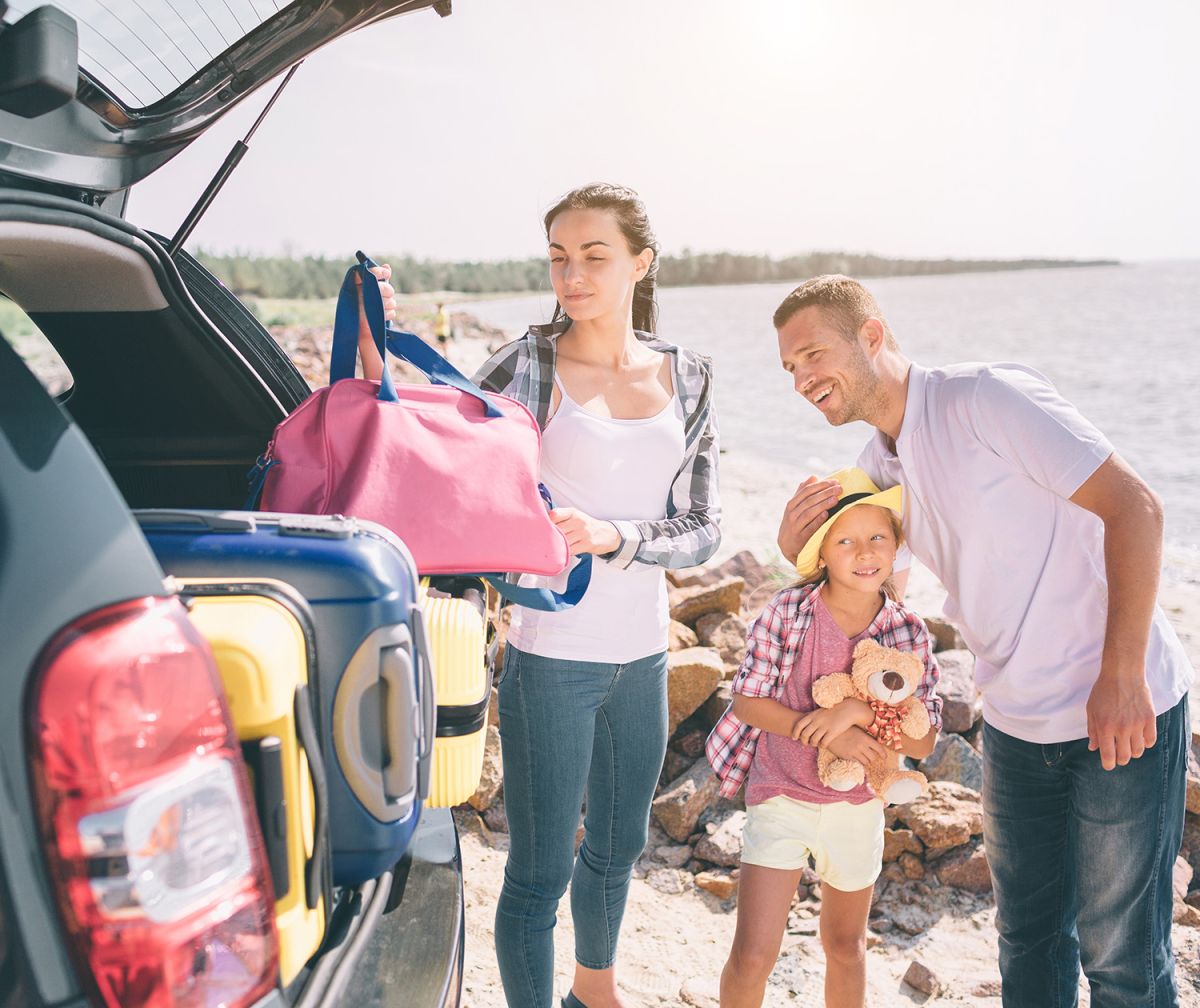 Eine Familie lädt das Auto mit Gepäck für den Sommerurlaub© Estrada Anton / Shutterstock.com